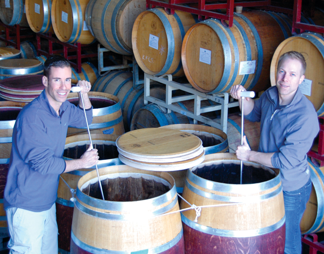 Cheers!: Ryan Levy (l) and Ian Eastveld in Napa Valley during the fermentation of their NICE Stags Leap District Cabernet Sauvignon. They ferment the old-fashioned way—in open-top French barrels. Here they are performing “punch-downs,” which is a process in which they incorporate the grape skins into the juice to add color and body. They have additional vineyards in Mendoza, Argentina, and Cypress, Texas.